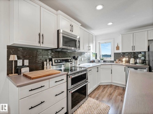 Bright kitchen featuring white shaker cabinetry, stainless steel appliances, dark subway tile backsplash, and recessed lighting - 162 Kirpatrick Way, Leduc, AB 