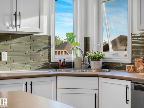 Corner kitchen sink with a stainless steel faucet, set against a mosaic tile backsplash - 162 Kirpatrick Way, Leduc, AB 