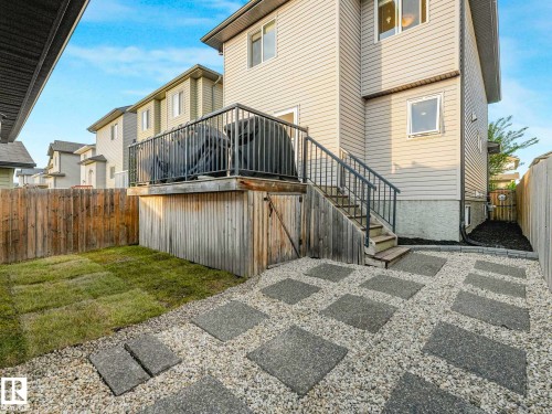 Rear exterior with vinyl siding and a wood deck featuring black metal railings - 162 Kirpatrick Way, Leduc, AB 
