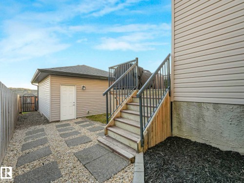 Side yard featuring a detached shed, wood privacy fencing, and a gravel pathway with stepping stones - 162 Kirpatrick Way, Leduc, AB 