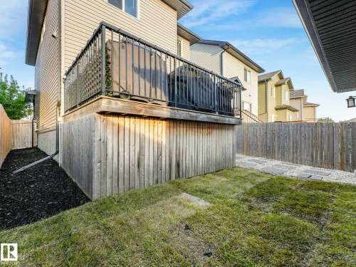 Raised wood deck with black metal railing, offering a private outdoor space - 162 Kirpatrick Way, Leduc, AB 