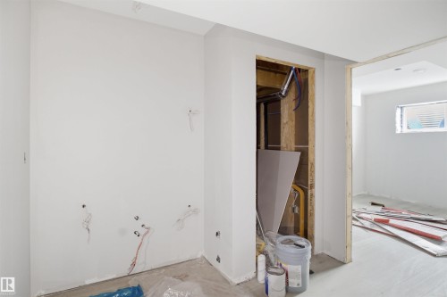 Unfinished interior space featuring a framed doorway opening, white primed walls, and exposed electrical wiring - 1222 Podersky Wynd, Edmonton, AB 