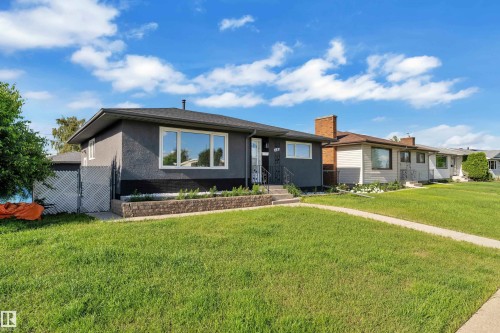 Contemporary exterior with dark stucco finish, white trim windows, and a black shingled roof - 8104 135 Avenue, Edmonton, AB 