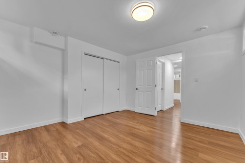 Room featuring wood-finish flooring, white walls, and a flush-mount ceiling light - 8104 135 Avenue, Edmonton, AB 