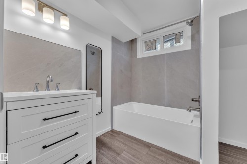 Modern bathroom featuring a white vanity with black hardware, a rectangular undermount sink, and a chrome widespread faucet - 8104 135 Avenue, Edmonton, AB 
