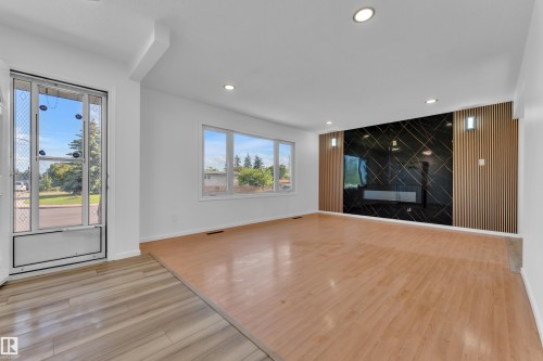 Spacious living area featuring a prominent black and gold accent wall with an integrated fireplace - 8104 135 Avenue, Edmonton, AB 