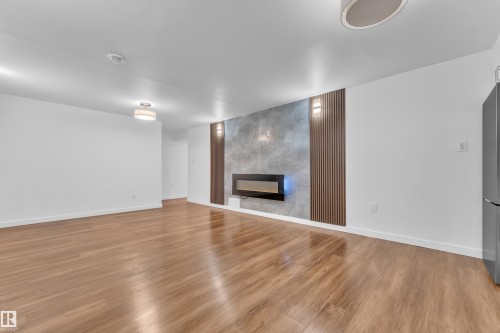 Spacious room with wood-finish flooring and white walls - 8104 135 Avenue, Edmonton, AB 