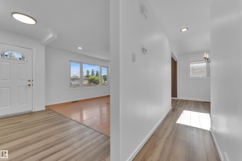 Entryway featuring a white paneled door with arched decorative glass, recessed lighting, and wood-finish flooring - 8104 135 Avenue, Edmonton, AB 