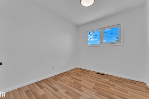 Bright room featuring wood-finish flooring and a large window - 8104 135 Avenue, Edmonton, AB 