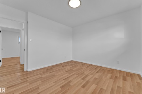 Bright interior space featuring wood-finish flooring, white walls, and a ceiling-mounted light fixture - 8104 135 Avenue, Edmonton, AB 