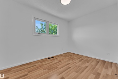 Room featuring wood-finish flooring, white baseboards, and a single window with white trim - 8104 135 Avenue, Edmonton, AB 