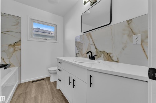 Bathroom featuring a white vanity with a single sink, black faucet, and white countertop - 8104 135 Avenue, Edmonton, AB 