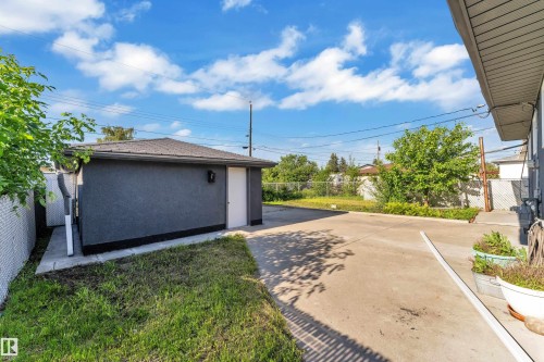 Detached garage with dark stucco exterior, white side entry door, and composition shingle roof - 8104 135 Avenue, Edmonton, AB 