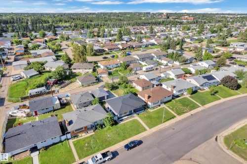 Aerial perspective showcasing a residential neighborhood with a mix of single-story homes, mature trees, and paved streets - 8104 135 Avenue, Edmonton, AB 