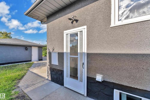 Exterior stucco finish with a white entry door featuring leaded glass detailing - 8104 135 Avenue, Edmonton, AB 
