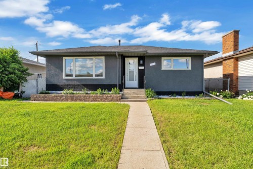 Contemporary single-story residence with a dark gray stucco exterior and white trim windows - 8104 135 Avenue, Edmonton, AB 