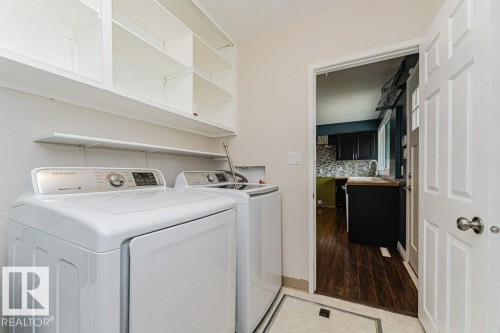 Dedicated laundry area featuring a white paneled door, built-in shelving, a wall-mounted shelf, and light-toned floor tiling - 13411 140 Street, Edmonton, AB 