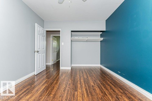 Interior room featuring wood-finish flooring, light gray walls, and an accent wall in teal - 13411 140 Street, Edmonton, AB 