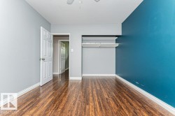 Interior room featuring wood-finish flooring, light gray walls, and an accent wall in teal - 