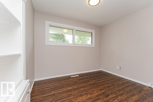 Room featuring wood-finish flooring, a contemporary ceiling light fixture, and a white framed window - 13411 140 Street, Edmonton, AB 
