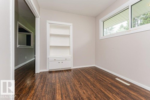 Wood-finish flooring throughout, featuring a built-in white shelving unit with lower cabinetry - 13411 140 Street, Edmonton, AB 
