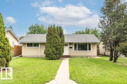 Single-story residence featuring a stucco exterior, gray shingle roof, and white-framed windows - 13411 140 Street, Edmonton, AB 