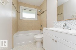 Bathroom featuring a white vanity with a single basin sink, contemporary chrome faucet, and a decorative scallop tile backsplash - 