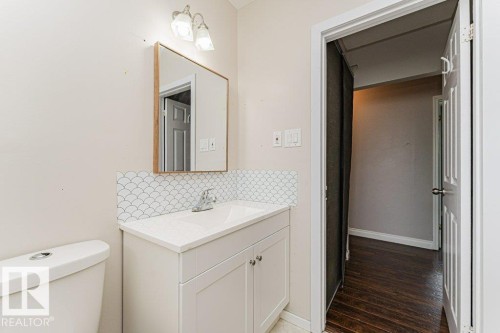 Vanity with a white countertop and integrated sink, complemented by a decorative scallop tile backsplash - 13411 140 Street, Edmonton, AB 