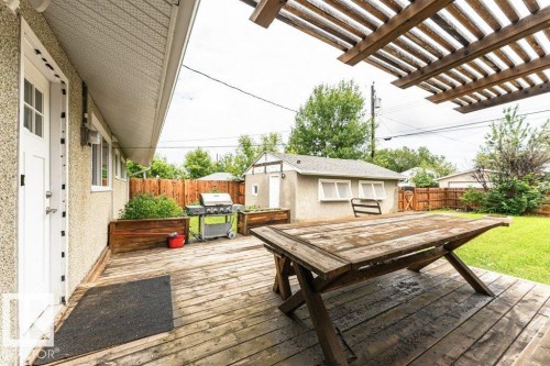Expansive wooden deck with an overhead pergola, offering direct access to the interior via a white paneled door - 13411 140 Street, Edmonton, AB 
