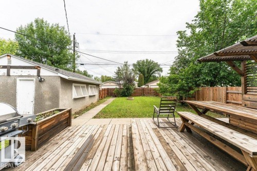Expansive backyard featuring a wood deck, built-in wooden picnic table with pergola, concrete patio, and a grassy area - 13411 140 Street, Edmonton, AB 