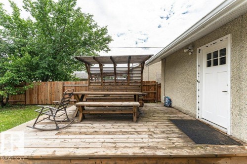 Expansive wood deck featuring a pergola, wood privacy fencing, and a white exterior door with window panes - 13411 140 Street, Edmonton, AB 
