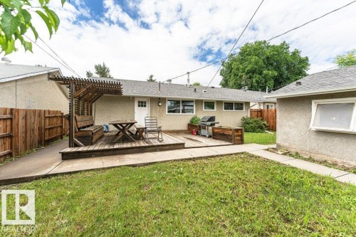 Expansive backyard with a wooden deck featuring a built-in pergola and bench seating - 13411 140 Street, Edmonton, AB 