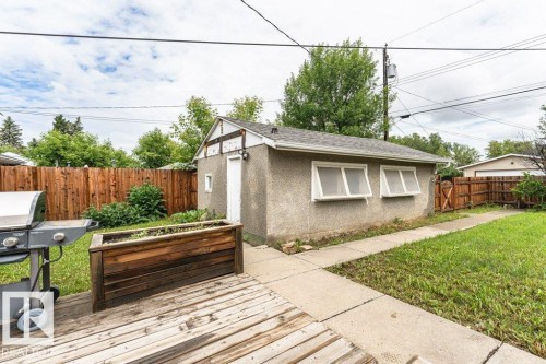 Detached garage featuring stucco exterior, multiple windows, and a side access door - 13411 140 Street, Edmonton, AB 