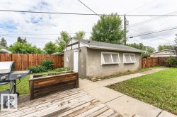 Detached garage featuring stucco exterior, multiple windows, and a side access door - 