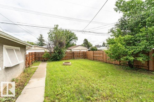 Fenced backyard featuring a manicured lawn, established trees, and a concrete pathway - 13411 140 Street, Edmonton, AB 