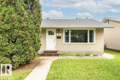 Exterior featuring stucco siding, a grey shingle roof, white trim windows, and a white paneled entry door with glass inserts - 13411 140 Street, Edmonton, AB 