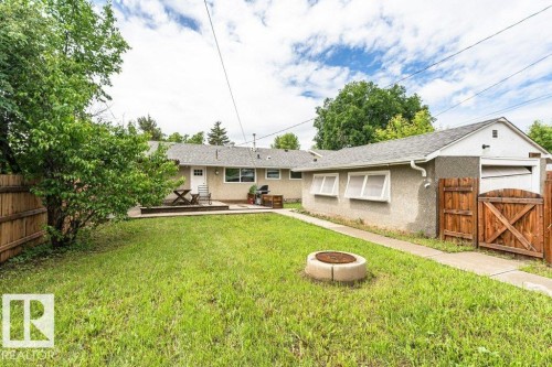 Expansive backyard featuring a central fire pit, concrete patio, and mature perimeter trees - 13411 140 Street, Edmonton, AB 