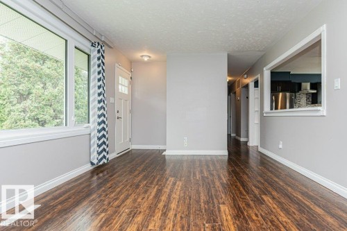 Open-concept living area featuring wood-finish flooring, white baseboards, and neutral wall tones - 13411 140 Street, Edmonton, AB 