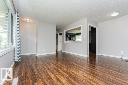 Spacious interior room featuring wood-finish flooring, light gray wall tones, and white trim - 13411 140 Street, Edmonton, AB 