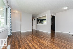 Spacious interior room featuring wood-finish flooring, light gray wall tones, and white trim - 
