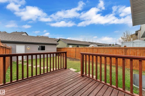 Spacious backyard featuring a wood deck with railings, a manicured lawn, and privacy fencing - 2143 32 Street, Edmonton, AB 