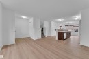 Open-concept main level featuring wood-finish flooring, a kitchen island with integrated sink, stainless steel dishwasher, and track lighting - 2143 32 Street, Edmonton, AB 