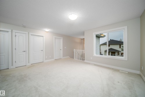 Carpeted room featuring multiple panel doors, white trim, and a prominent window - 11312 13 Ave Sw, Edmonton, AB 