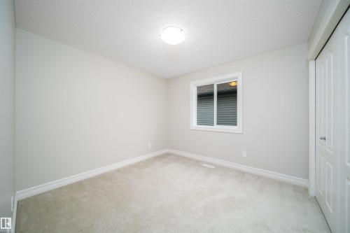 Spacious room featuring neutral carpeting, light gray wall paint, and white trim - 11312 13 Ave Sw, Edmonton, AB 