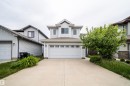 Two-story residence featuring light-colored siding, a prominent front-facing gable, and an attached two-car garage with divided light windows - 11312 13 Ave Sw, Edmonton, AB 