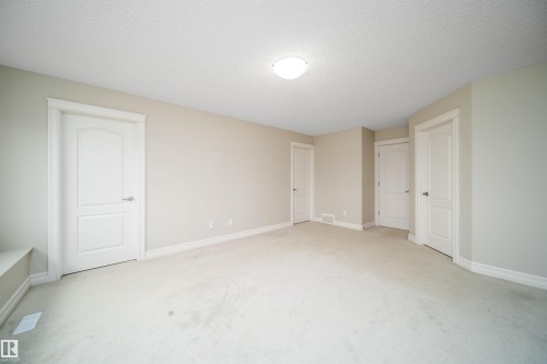 Neutral tone wall paint, white trim, light-colored carpeting, multiple white panel doors, and a ceiling-mounted light fixture - 11312 13 Ave Sw, Edmonton, AB 
