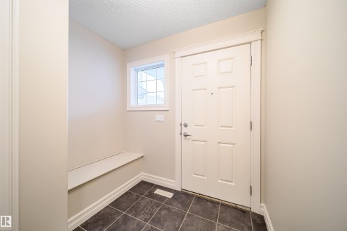 Entryway featuring a paneled door, square tile flooring, built-in bench, and a transom window - 11312 13 Ave Sw, Edmonton, AB 
