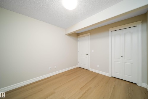 Room featuring wood-finish flooring, neutral wall tones, white trim, and a white ceiling with an overhead light fixture - 11312 13 Ave Sw, Edmonton, AB 