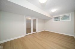 Well-lit room featuring wood-finish flooring, white baseboards, and a neutral wall color - 