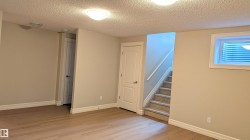 Spacious room featuring wood-finish flooring, light neutral wall paint, and white trim - 